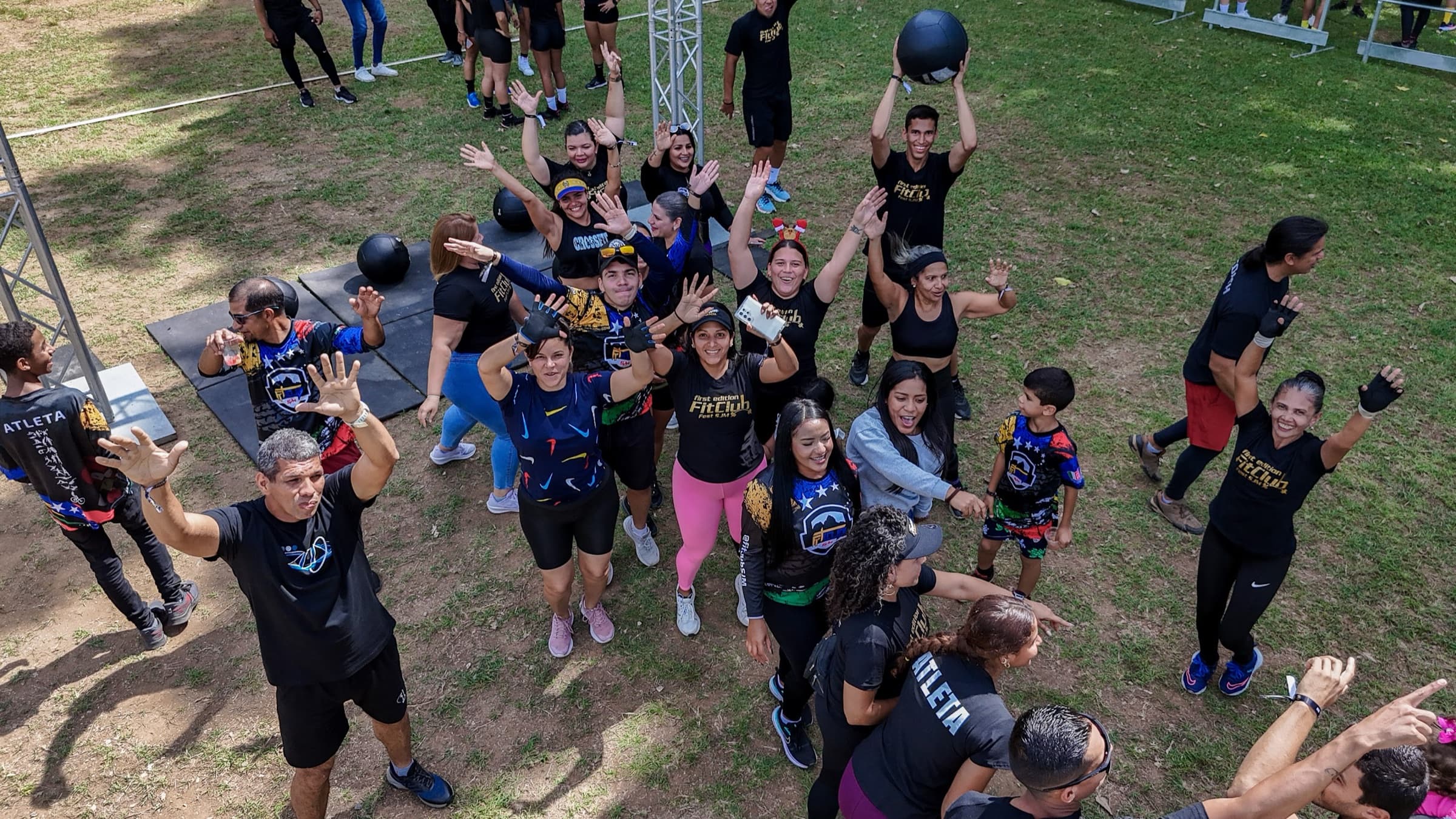 Atletas de Fit Club celebrando juntos con los brazos en alto durante el FitClub Fest