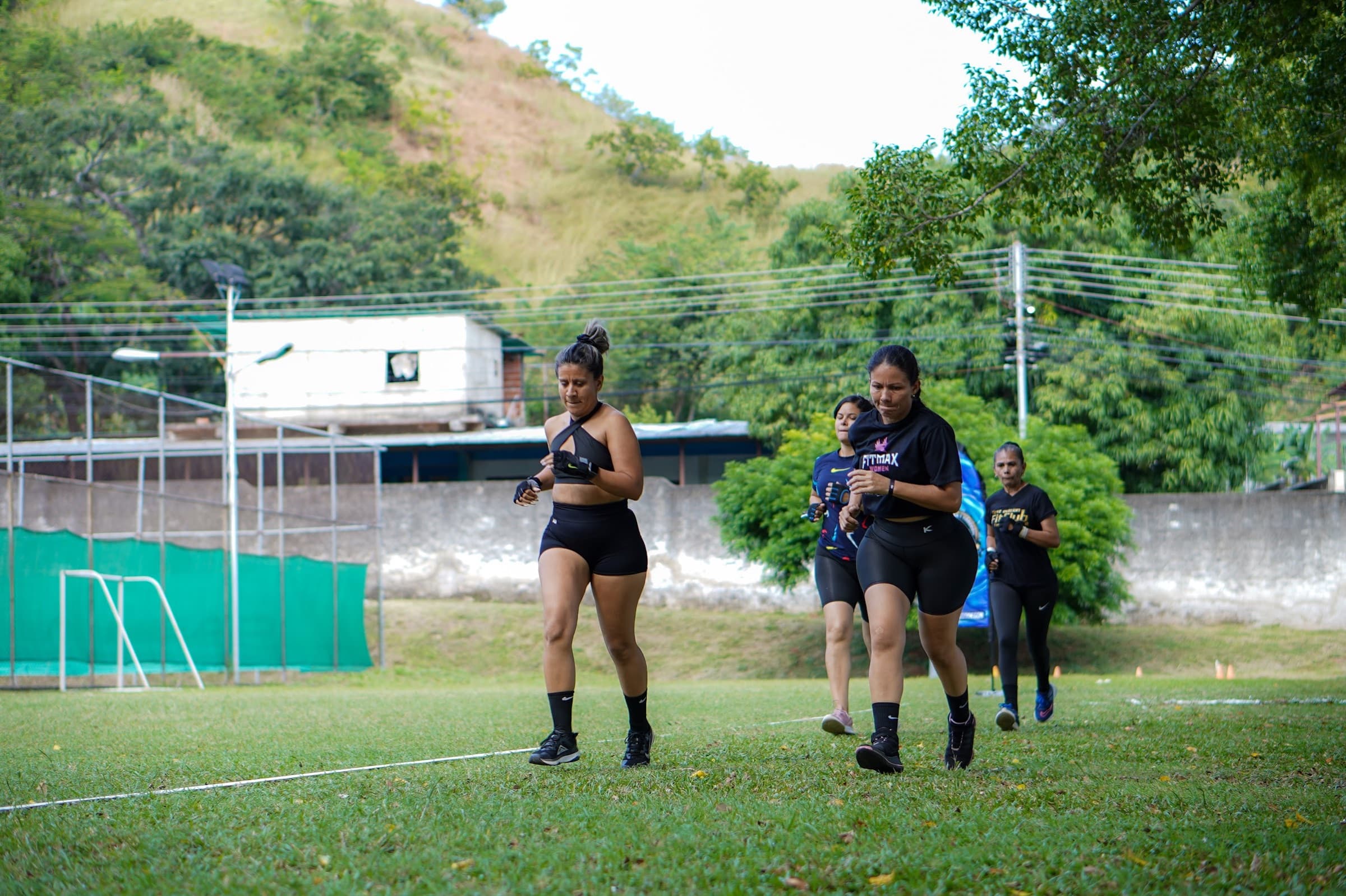 Atletas de Fit Club trotando sobre la grama con los cerros de San Juan de los Morros al fondo